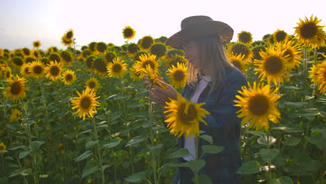 The-farmer-woman-is-watching-and-touching-the-sunflowers.-She-enjoys-the-great-weather-in-the-sunflower-field.-Beatifull-day-in-nature.
